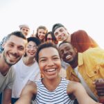 pexels-photo-36729918-36729918 A diverse group of friends taking a joyful selfie outdoors during sunset.